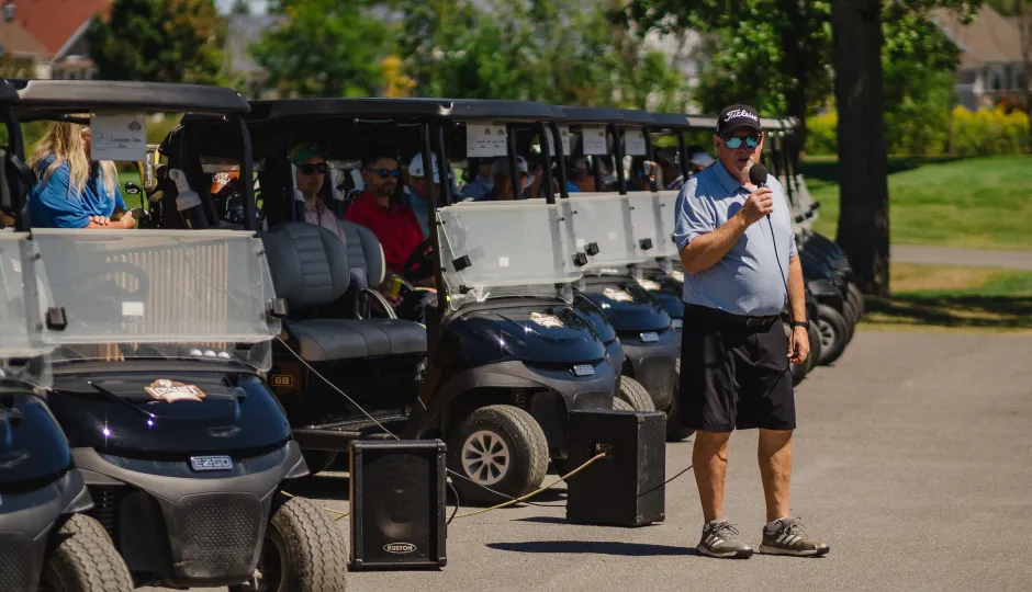 Man holding microphone talking to golfers