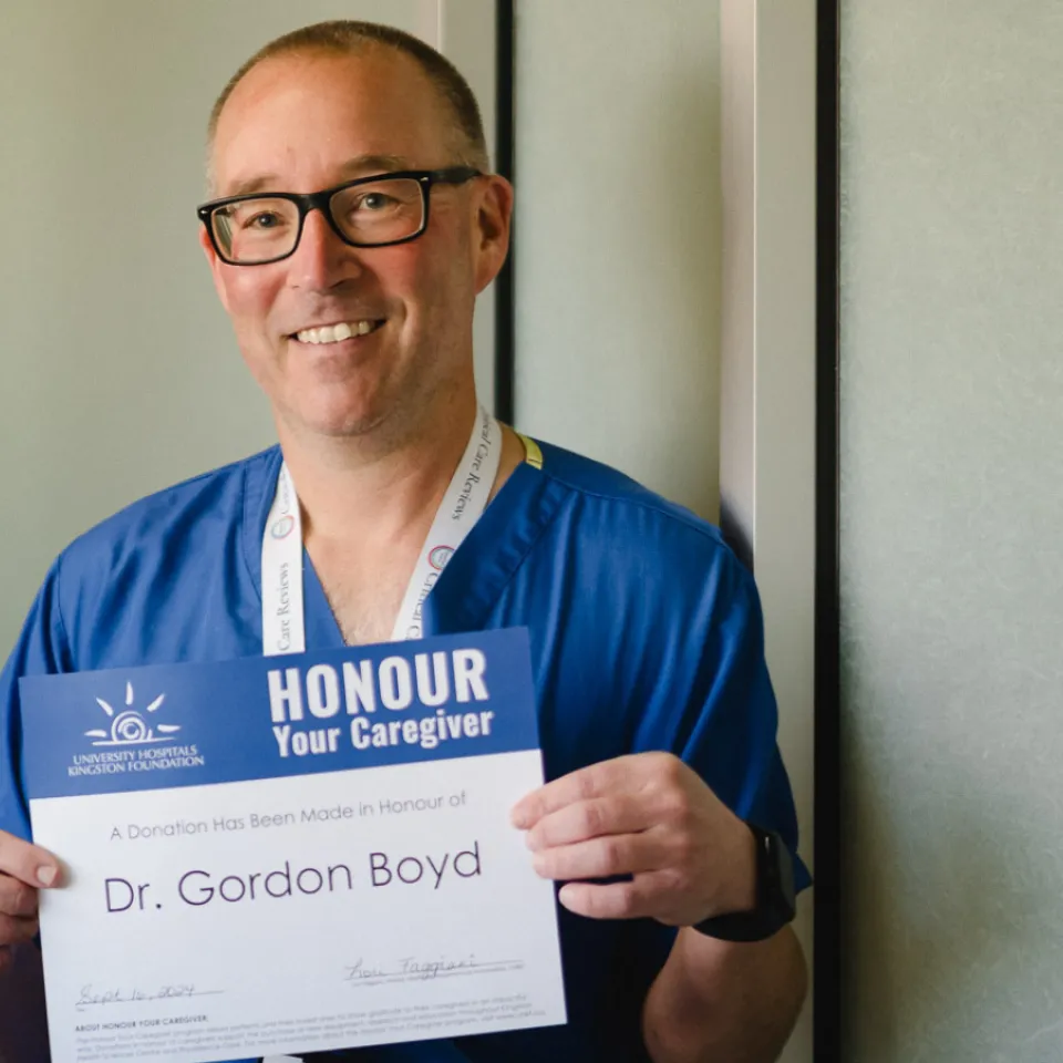 Dr. Gordon Boyd smiling and holding an Honour Your Caregiver certificate.